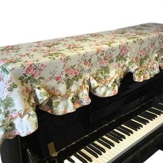 a black piano with a floral tablecloth on it