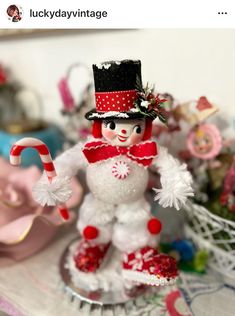 a snowman figurine sitting on top of a table next to candy canes