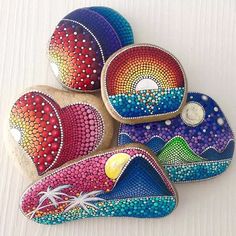 four painted rocks sitting on top of a white table next to each other with different designs