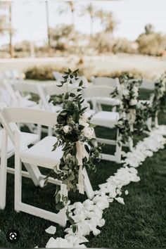 the aisle is lined with white flowers and greenery