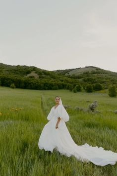 a woman in a wedding dress standing in the middle of a field