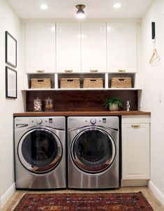 a washer and dryer in a small laundry room with white cabinets, rugs and baskets on the wall