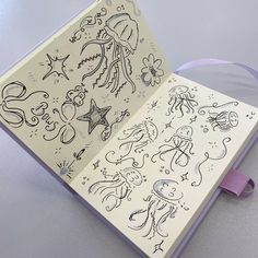 an open book with drawings on it and purple ribbon around the page, sitting on a table