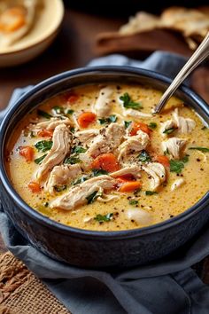 a bowl of soup with chicken, carrots and parsley in it on a table