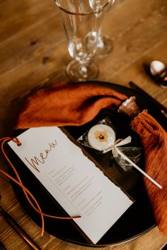 a table setting with menus and wine glasses on the wooden table, along with utensils