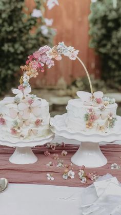 two tiered wedding cakes with pink flowers on top and white frosting sitting on a table