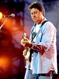 a man standing in front of a microphone holding a guitar