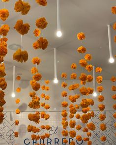 orange flowers are hanging from the ceiling in front of a sign that reads el churreo