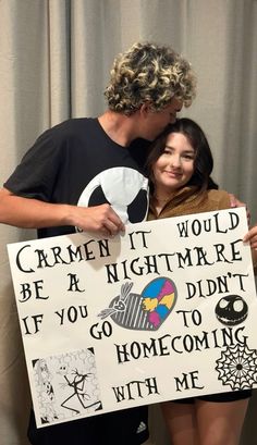 a man and woman standing next to each other holding a sign