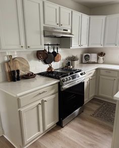 a kitchen with white cabinets and an oven in the center, along with utensils hanging on the wall