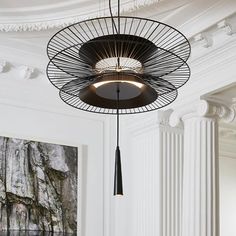 a ceiling fan hanging from the ceiling in a room with white walls and columns on either side