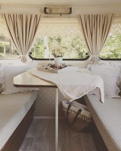 the inside of a camper with white linens and pillows