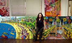 a woman standing in front of a large painting on the wall next to a wooden floor