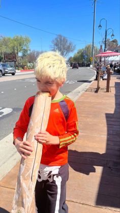 a young boy is holding a skateboard on the sidewalk