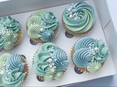 six cupcakes with blue and green frosting in a box