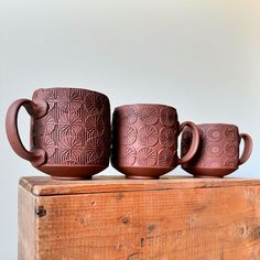 three brown cups sitting on top of a wooden box