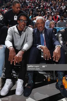 two men sitting next to each other in front of an audience at a basketball game