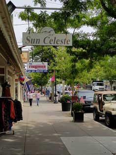 people walking down the sidewalk in front of shops and cars parked on the side walk