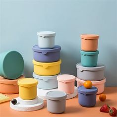 there are many different containers stacked on top of each other with fruit in the background