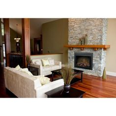 a living room with two couches and a fireplace in the center, surrounded by wood flooring