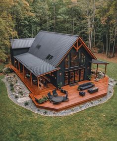 an aerial view of a house in the middle of a wooded area with patio furniture