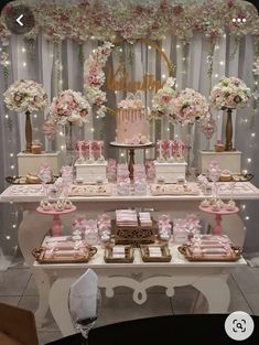 a table topped with lots of pink and white desserts next to a wall covered in flowers