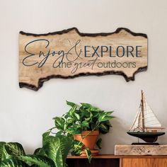 a wooden sign that says enjoy and explore the great outdoorss with a sailboat on it