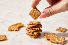 a person is picking up some crackers from the table