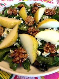 a salad with apples, walnuts and spinach leaves on a white platter