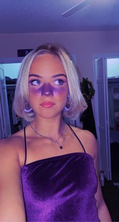 a woman in a purple dress is posing for the camera with her face painted like an alien