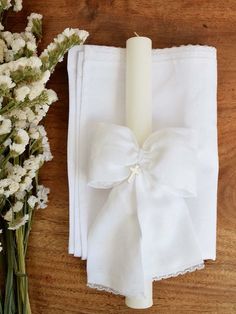 a white napkin with a bow tied around it next to a bouquet of flowers on a wooden table