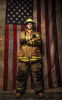 a firefighter standing in front of an american flag with his arms crossed and looking at the camera