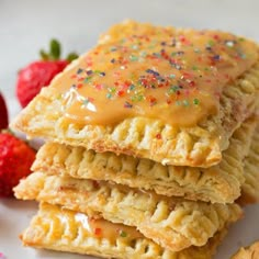 a stack of cookies with frosting and sprinkles next to strawberries