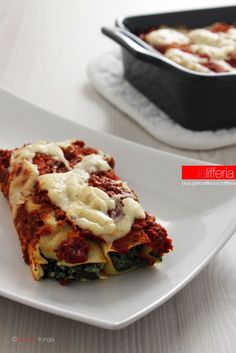 a white plate topped with lasagna next to a casserole dish on a table