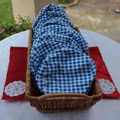 a wicker basket with a blue and white checkered cloth in it on top of a table