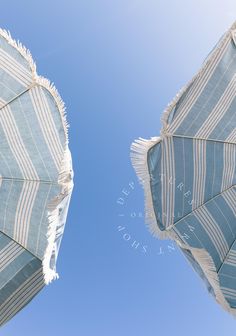 two blue and white striped umbrellas with the sky in the backgrouund