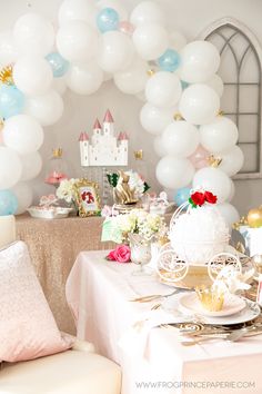 a table set up for a princess birthday party with balloons and decorations on the wall