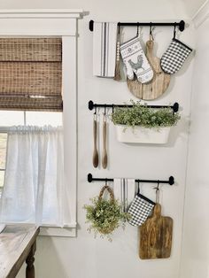 the kitchen wall is decorated with hanging utensils and potted plants, along with wooden cutting boards