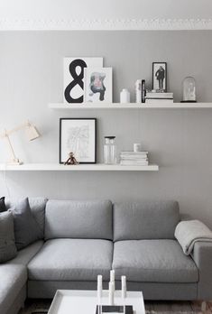 a couch and table in a room with shelves on the wall above it that are also displaying photos