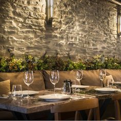 a table with place settings in front of a stone wall