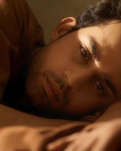 a man laying on top of a bed with his eyes closed and one eye open