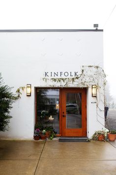 the front entrance to kinfolk's restaurant with potted plants on either side