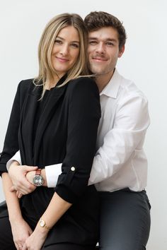 a man and woman sitting next to each other posing for the camera with their arms around each other