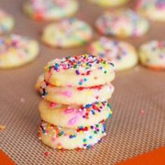 a stack of sprinkle covered cookies sitting on top of a cookie sheet