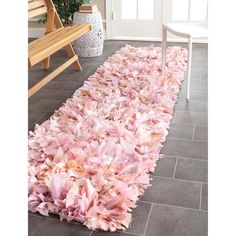 a long rug made out of pink flowers on the floor next to a wooden bench