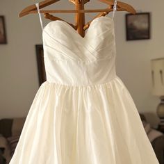 a white dress hanging on a wooden hanger