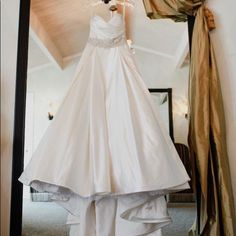 a wedding dress hanging in front of a mirror