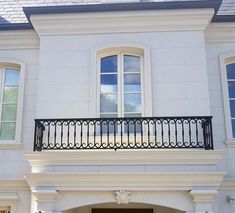 a white house with black iron balcony railing