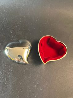 an open heart shaped box sitting on top of a table next to a metal object