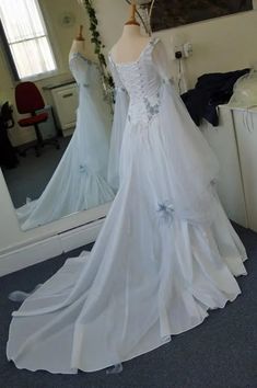 a white wedding dress on display in front of a mirror